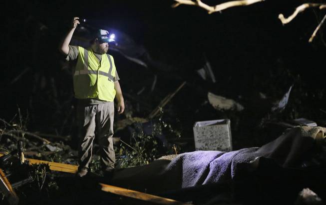A responder shines his flashlight into the remains of several mobile homes as he searches for survivors in Louisville, Miss., early Tuesday morning, April 29, 2014 after a tornado hit the east Mississippi community Monday.  