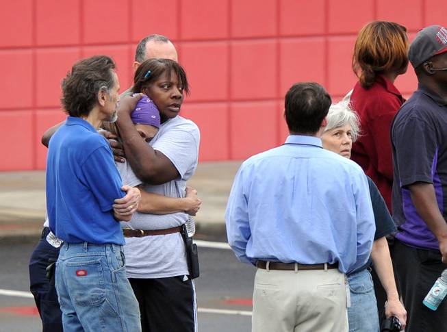 FedEx employee Lisa Aiken, is embraced by a co-worker as other FedEx employees gather following a shooting at the FedEx facility in Kennesaw, Ga., on Tuesday, April 29, 2014.