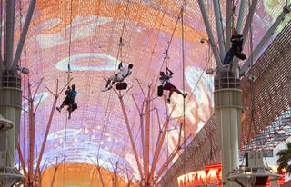 People pass under the Viva Vision canopy as they try out the  new 850-feet-long SlotZilla Zipline at the Fremont Street Experience in downtown Las Vegas, Wednesday, April 30, 2014. A higher and longer 1700-feet-long Zoomline, which will propel flyers in a horizontal 