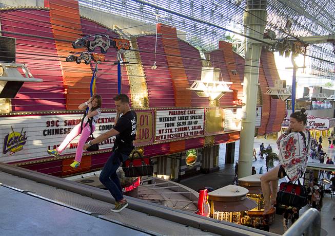 Cirque du Soleil performers Jason Beitel, center, and Jenn Stafford, right, arrive at a landing ramp after riding the 850-feet-long SlotZilla Zipline at the Fremont Street Experience in downtown Las Vegas, Wednesday, April 30, 2014. A higher and longer 1700-feet-long Zoomline, which will propel flyers in a horizontal "superman" position at speeds up to 35 mph, is expected to open in June. The zip-line, part of the $12 million SlotZilla project, opened April 27, 2014.