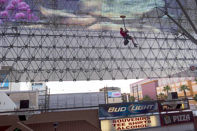 A "flyer" passes under the Viva Vision canopy as he tries out the  new 850-feet-long SlotZilla Zipline at the Fremont Street Experience in downtown Las Vegas, Wednesday, April 30, 2014. A higher and longer 1700-feet-long Zoomline, which will propel flyers in a horizontal "superman" position at speeds up to 35 mph, is expected to open in June. The zip-line, part of the $12 million SlotZilla project, opened Sunday.