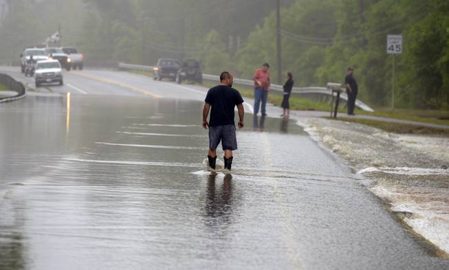 A man walks along a flooded stretch of Mobile Highway in Beulah, Fla., following heavy rains near Pensacola, Fla., Wednesday, April 30, 2014.
