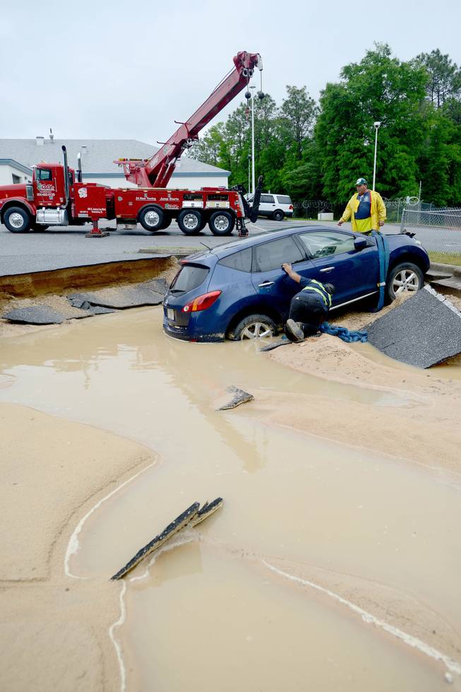 A wrecking crew tries to lift a car out of the parking lot of the Okaloosa County Jail in Crestview, Fla. on Wednesday, April 30, 2014, after flood waters washed out a portion of the concrete. Much of Northwest Florida experienced flooding as a result of heavy sustained rains Tuesday and Wednesday. 