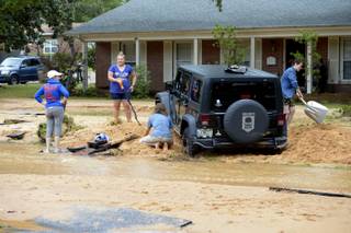 Barbara Erdos, far left, watches as Marguerite Lysek, left, Dr. Zoltan Erdos, kneeling, and Kristen Broussard, right help dig Erdos' stuck Jeep out of axel-deep mud on Piedmont Street after flood-water devastation caused by torrential rains in Pensacola, Fla., Wednesday, April 30, 2014.
