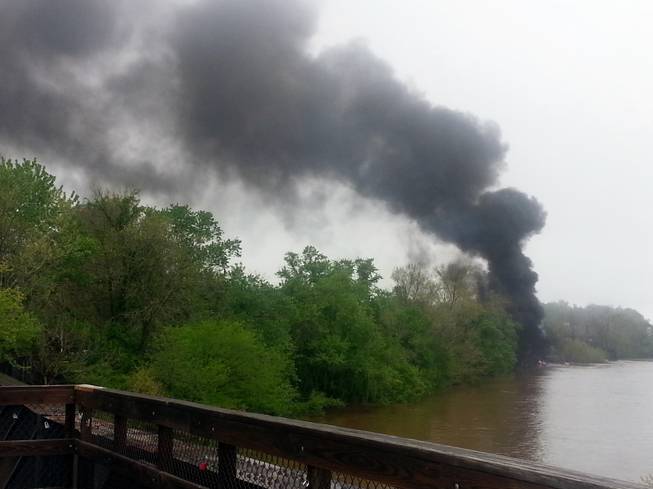 This mobile phone photo provided Ali Hallock shows smoke rising after several CSX tanker cars carrying crude oil derailed, from the view of a bridge over the James river, Wednesday, April 30, 2014, in Lynchburg, Va. Authorities evacuated numerous buildings Wednesday after the derailment.
