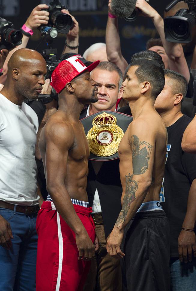 WBC welterweight champion Floyd Mayweather Jr., left,  and WBA champion Marcos Maidana of Argentina face off during an official weigh-in at the MGM Grand Garden Arena Friday, May 2, 2014. The two champions will meet in a WBC/WBA unification fight at the arena on Saturday.