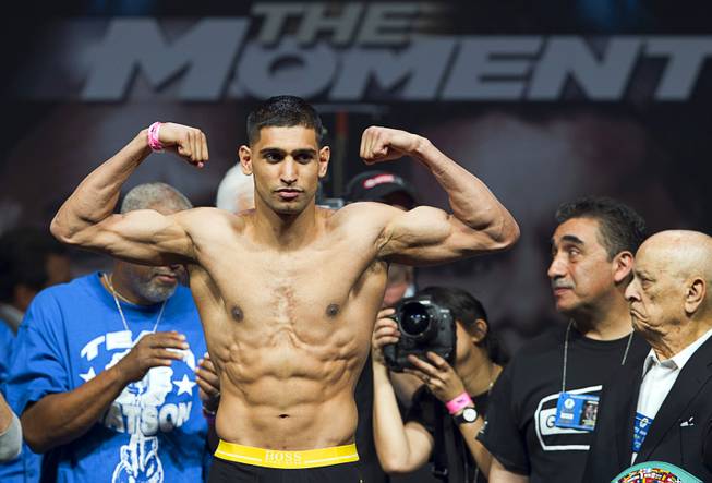 Amir Khan of Britain poses on the scale during an official weigh-in at the MGM Grand Garden Arena Friday, May 2, 2014. Khan will face Luis Collazo  for a welterweight fight at the arena on Saturday.