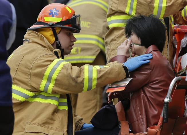 A New York City fire department EMT assists a woman who was evacuated from a subway train after it derailed in the Queens borough of New York, Friday, May 2, 2014.