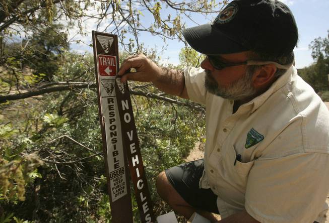 In this May 6, 2010, photo, Bureau of Land Management's Monticelllo Field Office Manager Tom Heinlein places a BLM "No Vehicles" placard at the trail head of Recapture Canyon on the northern outskirts of Blanding, Utah.