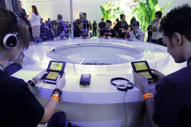In this June 11, 2013, file photo, attendees play video games on the Nintendo 3DS at the Nintendo Wii U software showcase during the E3 game show in Los Angeles. The gaming company came under fire in May 2014 after refusing to add same-sex relationship options to the game "Tomodachi Life."