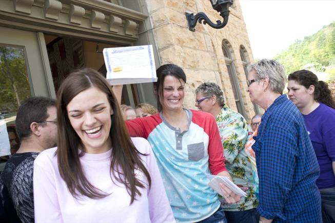 Kristin Seaton, center, of Jacksonville, Ark., holds up her marriage license as she leaves the Carroll County Courthouse in Eureka Springs, Ark., with her partner, Jennifer Rambo, left, of Fort Smith, Ark. Saturday, May 10, 2014, in Eureka Springs, Ark. Rambo and Seaton were the first same-sex couple to be granted a marriage license in Eureka Springs after a judge overturned Amendment 83, which banned same-sex marriage in the state of Arkansas.