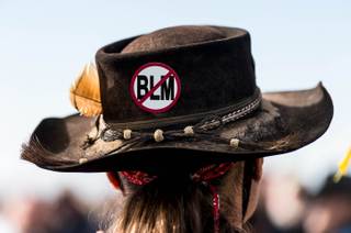 A protester, wearing an anti-Bureau of Land Management sign on his hat, listens to San Juan County Commissioner Phil Lyman at Centennial Park in Blanding, Utah on Saturday, May 10, 2014. Lyman organized an ATV protest ride into Recapture Canyon to show that the federal agency isn't the 