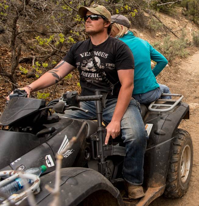 An ATV rider holds his finger near the trigger of his assault rifle as he and others make their way into Recapture Canyon, north of Blanding, Utah, on Saturday, May 10, 2014, in a protest against what demonstrators call the federal government's overreaching control of public lands. The area has been closed to motorized use since 2007 when an illegal trail was found that cuts through Ancestral Puebloan ruins. The canyon is open to hikers and horseback riders.
