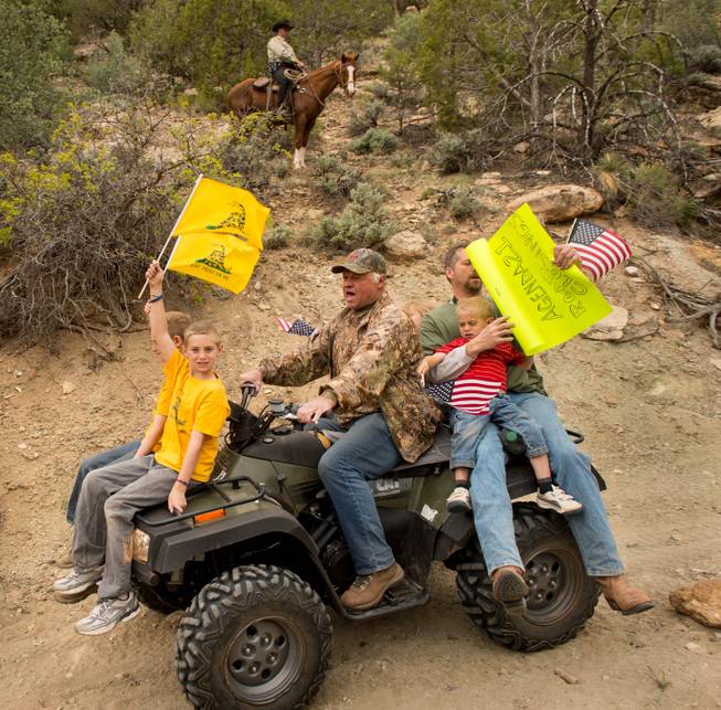 As a Kane County sheriff's deputy watches from a horse, ATV riders make their way into Recapture Canyon, north of Blanding, Utah, on Saturday, May 10, 2014, in a protest against what demonstrators call the federal government's overreaching control of public lands. The area has been closed to motorized use since 2007 when an illegal trail was found that cuts through Ancestral Puebloan ruins. The canyon is open to hikers and horseback riders.