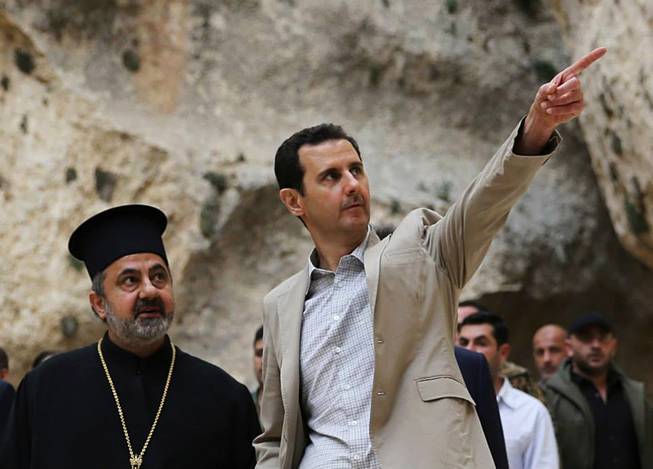 In this Sunday, April 20, 2014 file photo, released by the Syrian official news agency SANA, Syrian President Bashar Assad, right, visits the Christian village of Maaloula, near Damascus, Syria. Two years ago, it seemed almost inevitable that President Bashar Assad would be toppled. Almost no one thinks that now. As he prepares for elections through which he is set to claim another seven-year mandate for himself, the momentum in the civil war is clearly in Assad's favor.