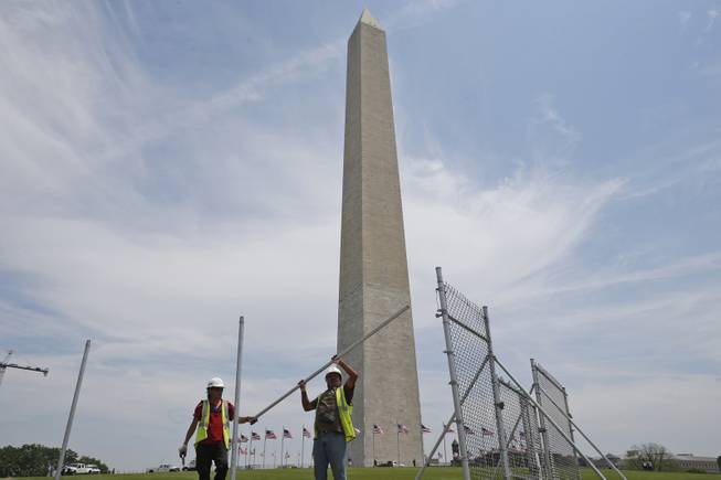 Workers Julio Dichis, right, and Jose Oreyana remove the fencing which closed the Washington Monument off to the public during renovations Washington, Friday, May 9, 2014. The monument, which sustained damage from an earthquake in August 2011, will re-open to the public on Monday, May 12, 2014. 