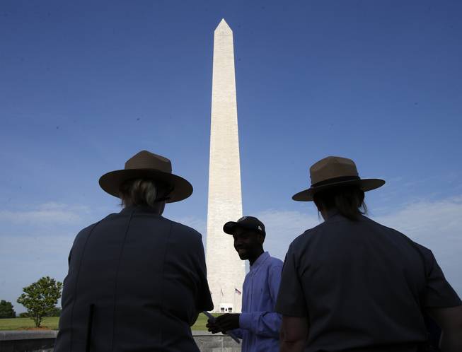 Park Service employees stand watch as visitor Roman Tanner, center, walks away with his Washington Monument ticket, which are distributed at on a first-come basis at the Washington Monument in Washington, Monday, May 12, 2014, ahead of a ceremony to celebrate its re-opening.