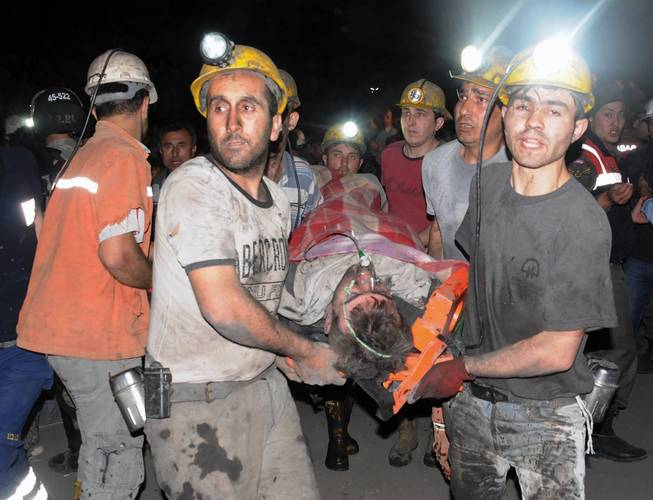 Miners carry a rescued miner after an explosion and fire at a coal mine killed at least 17 miners and left up to 300 workers trapped underground, in Soma, in western Turkey, Tuesday, May 13, 2014, a Turkish official said.