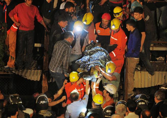 Miners carry a rescued friend hours after an explosion and fire at a coal mine killed at least 17 miners and left up to 300 workers trapped underground, in Soma, in western Turkey, late Tuesday, May 13, 2014, a Turkish official said.