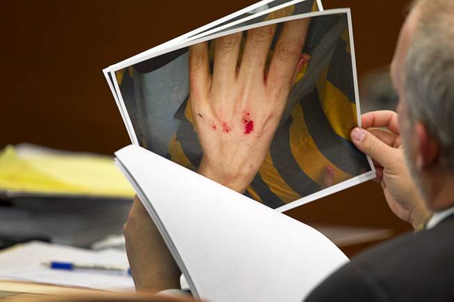 Prosecutor Marc DiGiacomo looks over defense photos during a trial for Jason Omar Griffith at the Regional Justice Center Wednesday, May 14, 2014. Griffith is accused of murdering Luxor "Fantasy" dancer Deborah Flores Narvaez in December 2010. The photos show injuries to Flores Narvaez after she broke Griffith's bedroom window.