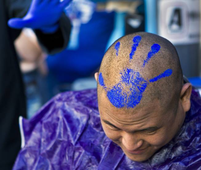 Zappos audio-visual team member Mikey Maneeraj shows off his fresh haircut and blue-paint hand stamp during the 10th Annual Zappos Bald and Blue charity event on Wednesday, May 15, 2014.