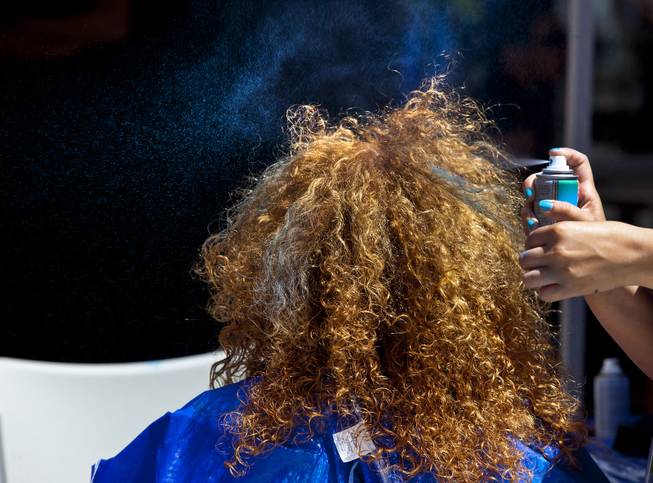 Blue hairspray is applied to strands of hair of a Zappos employee during their 10th Annual Zappos Bald and Blue charity event on Wednesday, May 15, 2014.