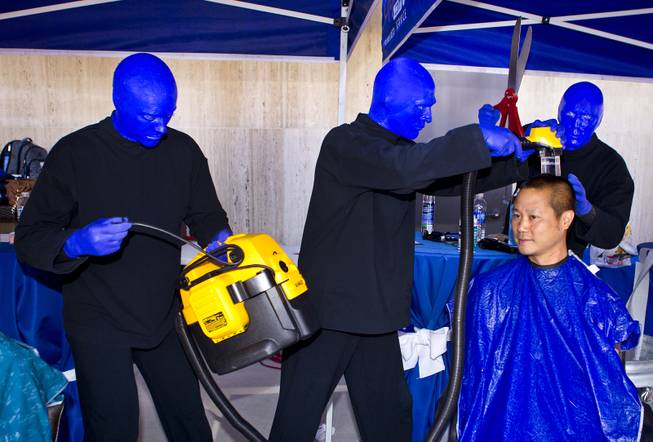 The Blue Man Group members joke with Zappos CEO Tony Hsieh as he readies for a haircut during the 10th Annual Zappos Bald and Blue charity event on Wednesday, May 15, 2014.