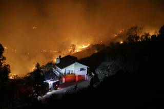 AP10ThingsToSee - A wildfire burns near a home on Wednesday, May 14, 2014, in San Marcos, Calif. Flames engulfed suburban homes and shot up along canyon ridges in one of the worst of several blazes that broke out Wednesday in Southern California during a second day of a sweltering heat wave. (AP Photo)