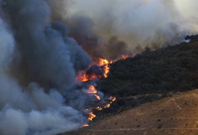 A wildfire burns along the hillside on Wednesday, May 14, 2014, in San Marcos, Calif. Flames engulfed suburban homes and shot up along canyon ridges in one of the worst of several blazes that broke out Wednesday in Southern California during a second day of a sweltering heat wave, taxing fire crews who fear the scattered fires mark only the beginning of a long wildfire season. (AP Photo)