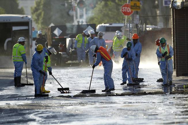 Crews sop up the remains of about 10,000 gallons of crude oil in the Atwater Village section of Los Angeles on Thursday, May 15, 2014. A geyser of crude spewed 20 feet high over approximately half mile into Los Angeles streets and onto buildings early Thursday after a high-pressure pipe burst.