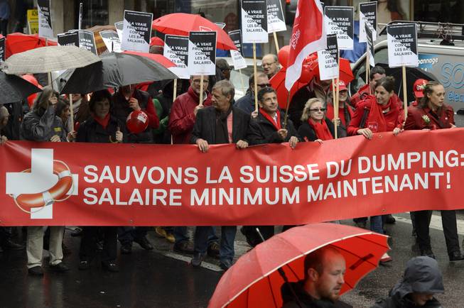 In this picture taken May 1, 2014, demonstrators carry a banner reading "Let's save Switzerland from dumping: wage minimum now!" in Geneva, Switzerland.