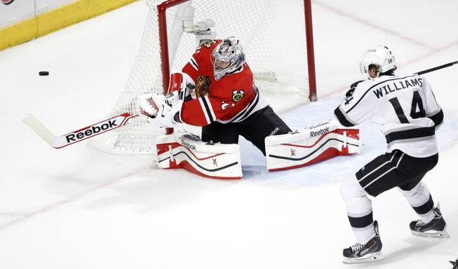 Chicago Blackhawks goalie Corey Crawford (50) clears the puck away from Los Angeles Kings right wing Justin Williams (14) during the second period of Game 1 of the Western Conference finals in the NHL hockey Stanley Cup playoffs in Chicago on Sunday, May 18, 2014.