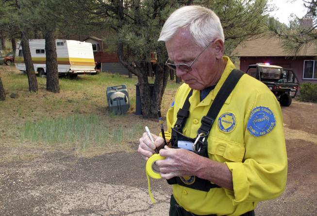 Dennis Gill with the Coconino County search and rescue team tags homes in Kachina Village, Ariz., where residents were warned on Wednesday, May 21, 2014, that they might have to evacuate because of a wildfire. Hundreds of firefighters poured into northern Arizona to battle the wind-whipped blaze. 