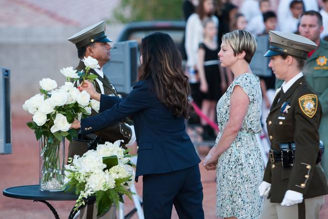 As the names of fallen officers are read, the family of fallen LVMPD Officer David VanBuskirk adds a white rose in his memory to the memorial bouquet during the Southern Nevada Law Enforcement Memorial ceremony at Police Memorial Park in Las Vegas Thursday, May 22, 2014.