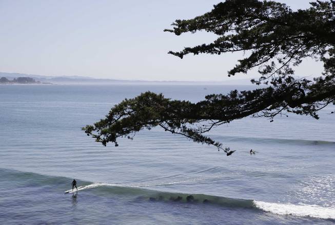 A woman surfs along the coastline near Cowell Beach in Santa Cruz, Calif., on Monday, April 7, 2014.