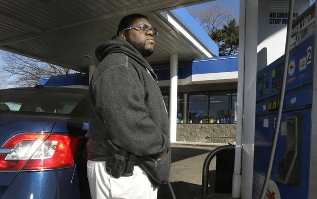 In a photo from April 9, 2014, Greg Champion wears a gun while pumping gas in Detroit. To avoid becoming a carjacking victim, Champion wears a handgun on his hip whenever he’s pumping gas. Through May 19, Detroit has recorded 191 carjackings in 2014.