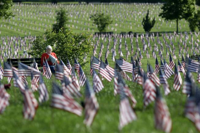 John Walaszek, of Old Bridge, N.J., is surrounded by flags for Memorial Day, as he relaxes on a bench at Brig. Gen. William C. Doyle Veterans Memorial Cemetery in Wrightstown, N.J., Sunday, May 25, 2014.