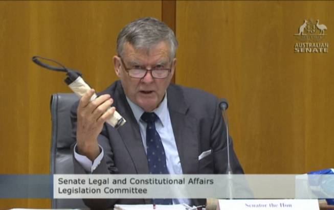 In this image made from ABC video, Sen. Bill Heffernan shows a fake pipe bomb during a committee hearing in Canberra, Australia, on Sunday, May 25, 2014. Heffernan, who represents the ruling Liberal Party, was making a point about a relaxation of security at Parliament House.