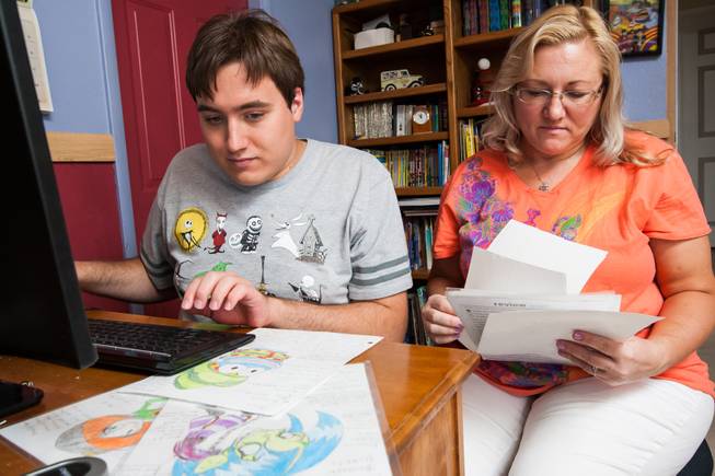 Author Ben Nelson, 20, who is autistic and has recently published his first book "Little Red Flying Hood," studies his artwork of characters in his new upcoming comic book alongside his mom, Laura, while working at his home in Henderson May 23, 2014.
