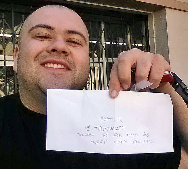 This image provided by Sergio Loza shows Loza holding up an envelope that had cash hidden in it in San Francisco on Sunday, May 25, 2014. Loza followed the clues from a Twitter user using the handle @HiddenCash to find the money. 