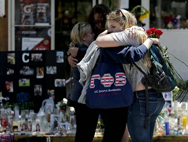 Mourners hug in front of the IV Deli Mart, where part of Friday night's mass shooting took place, on Tuesday, May 27, 2014 in the Isla Vista area near Goleta, Calif. Sheriff's officials said Elliot Rodger, 22, went on a rampage near the University of California, Santa Barbara, stabbing three people to death at his apartment before shooting and killing three more in a crime spree through a nearby neighborhood. 
