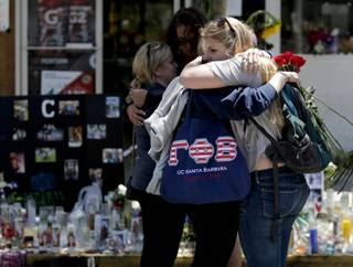 Mourners hug in front of the IV Deli Mart, where part of Friday night's mass shooting took place, on Tuesday, May 27, 2014 in the Isla Vista area near Goleta, Calif. 