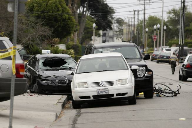Police tap marks of the scene where a black BMW sedan, left, driven by a drive-by shooter, rests on Saturday, May 24, 2014, in Isla Vista, Calif. 