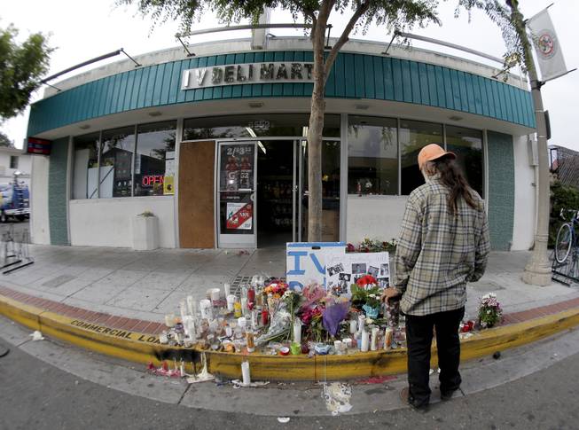 A passerby pays his respects at a makeshift memorial in front of the IV Deli Mart, Sunday, May 25, 2014, the scene of a drive-by shooting Friday in the Isla Vista area near Goleta, Calif. 