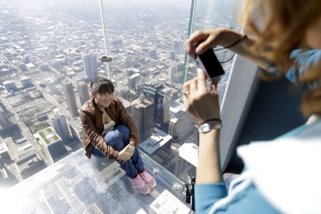 A tourist is photographed on the floor of one of four transparent ledges that jut out from the 103rd floor of the Willis Tower in Chicago on Thursday, May 29, 2014. 