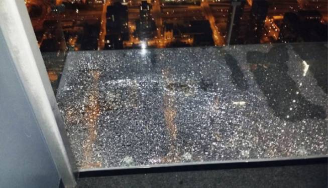 This Wednesday, May 28, 2014 photo provided by Alejandro Galibay shows the cracked coating of one of the glass bay of The Ledge, a popular tourist attraction on the 103rd story of the Willis Tower in Chicago. It started cracking when Galibay, of Stockton, Calif., his brother and two cousins, were sitting inside the transparent box. Garibay said Thursday, May 29, he knows now he wasn't in danger but when he first heard what sounded like breaking ice, he thought he was going to die. 