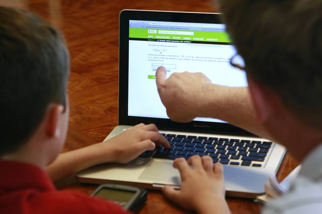 Tutor Michael Christenson uses an online program with Aidan Swenson during a tutoring session in the Swenson's home Saturday, May 31, 2014.