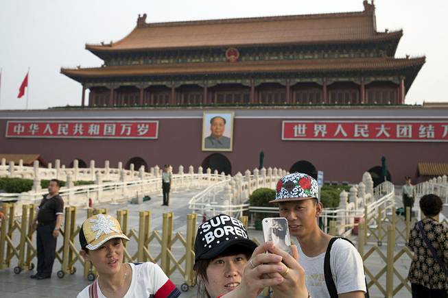 A Chinese woman takes a selfie on her mobile phone in front of Tiananmen Gate in Beijing Wednesday, June 4, 2014. Authorities in Beijing blanketed the city center with heavy security Wednesday on the 25th anniversary of the bloody military suppression of pro-democracy protests centered on Tiananmen Square. 
