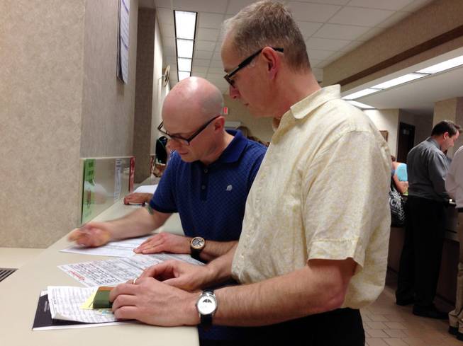 Mark Williams, left, and Chrisopher Martell, right, fill out an application for a marriage license at the Milwaukee County Clerk's office Friday, June 6, 2014, in Milwaukee. Same-sex couples began getting married in Wisconsin on Friday shortly after a federal judge struck down the state's gay marriage ban and despite confusion over the effect of the ruling.
