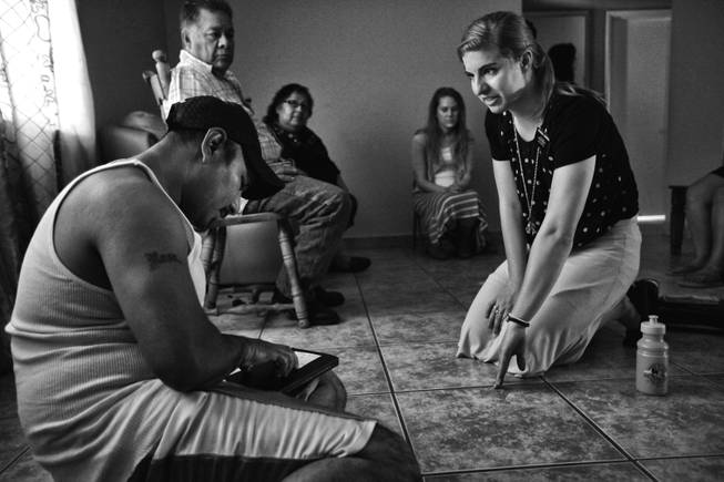 Francisco Galvez, sits on the floor of his home as a Mormon missionary makes her pitch to him and his family in Huron, California. During the season the areas farms need the most labor the work force doubles, but a drought has cut production and workers find trouble landing positions in the fields.